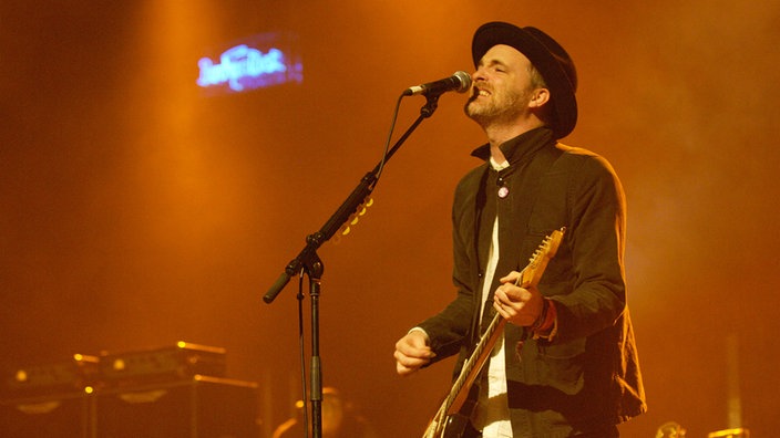 Fran Healy von Travis spielt auf der Bühne Gitarre und singt ins Mikrofon