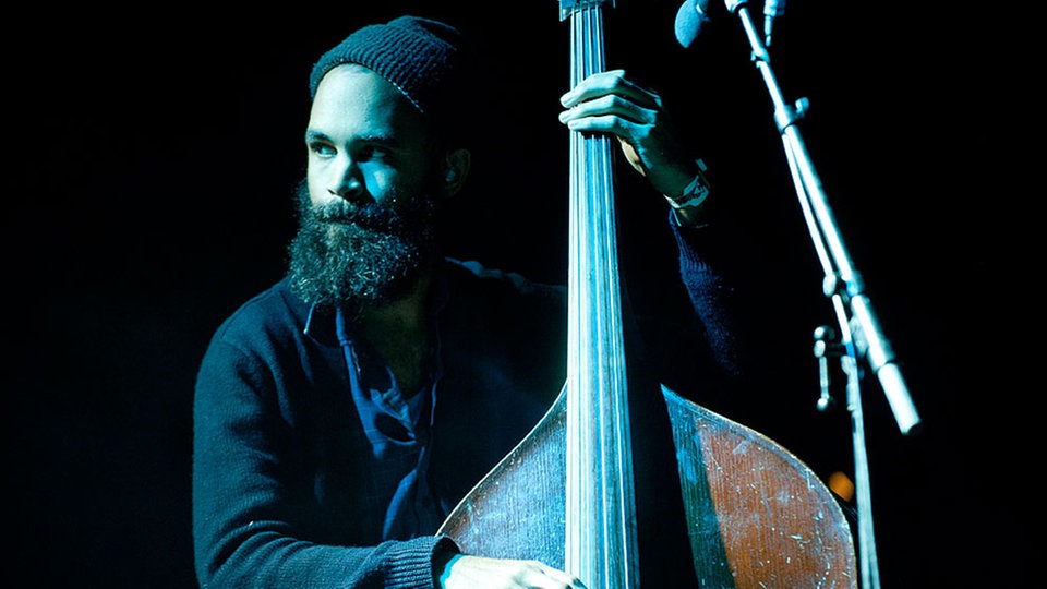 Eines der Bandmitglieder steht an einem großen Contrabass.