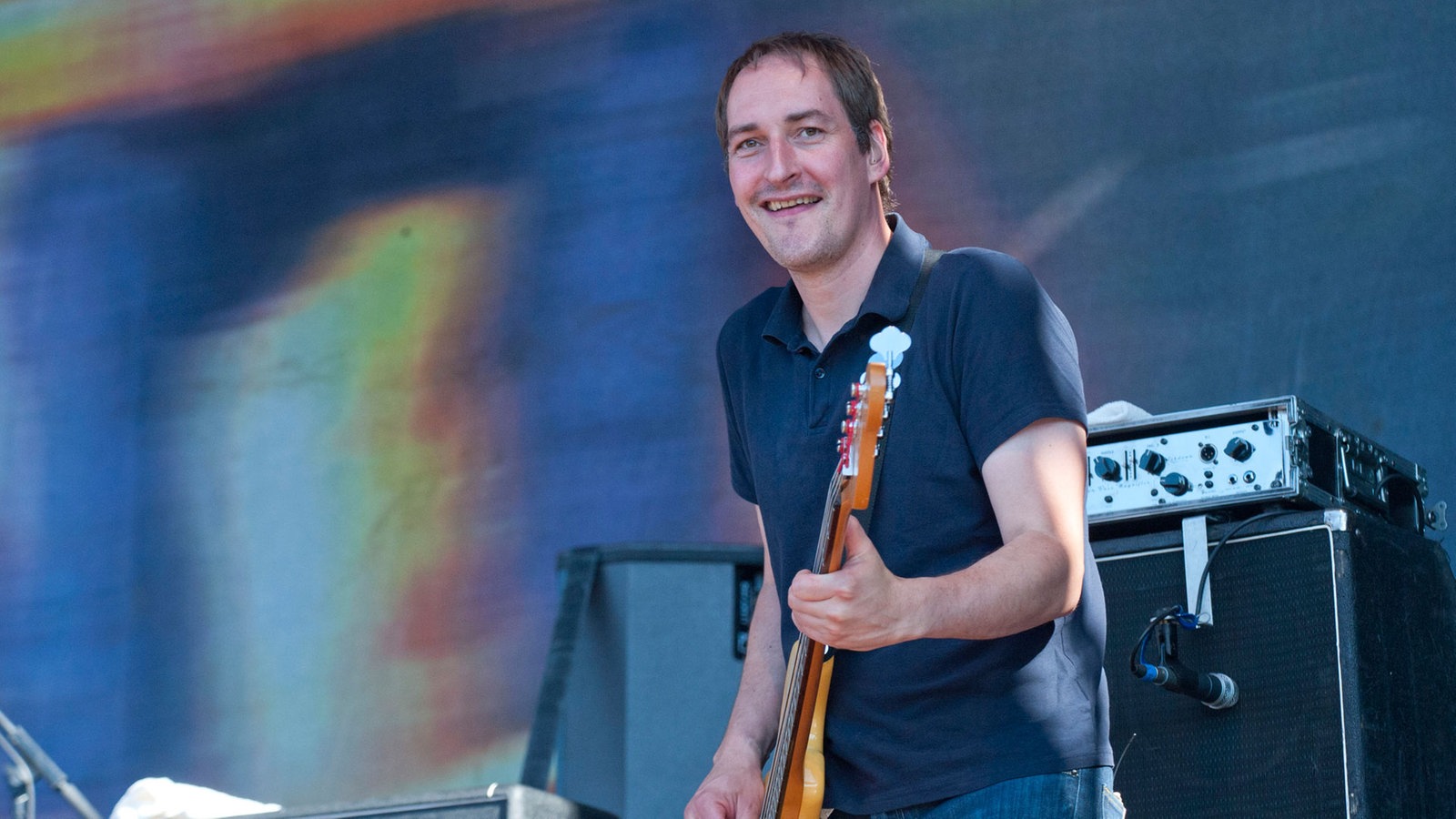 Bassist der Band Kettcar spielt und lacht dabei.