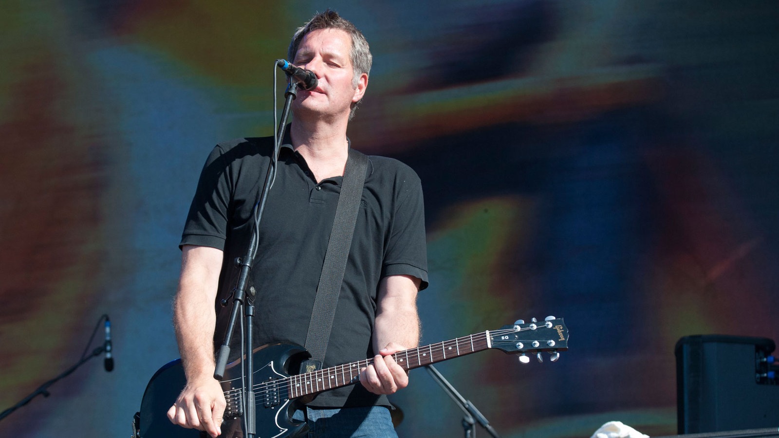 Mann spielt Gitarre und singt mit geschlossenen Augen
