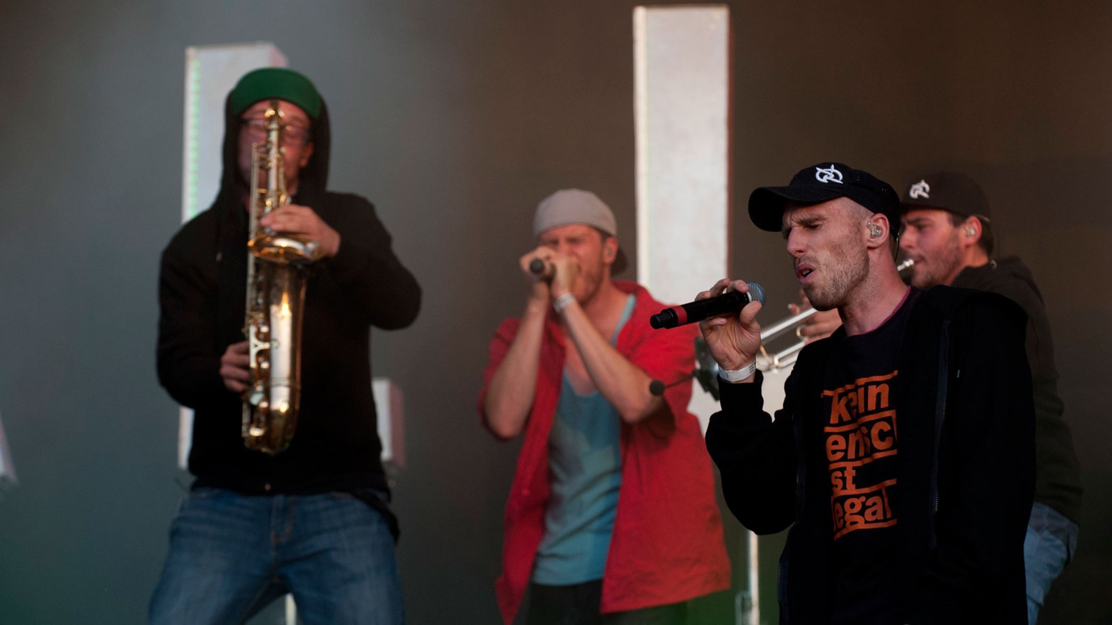 Zwei sänger stehen mit einem Saxophonisten und einem Trompetisten zusammen
