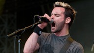 Der Frontmann singt ins Mikro, er hat blondgefärbte haare