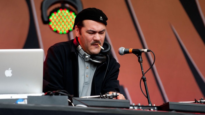 Der DJ raucht während er seine Plattenspieler einstellt
