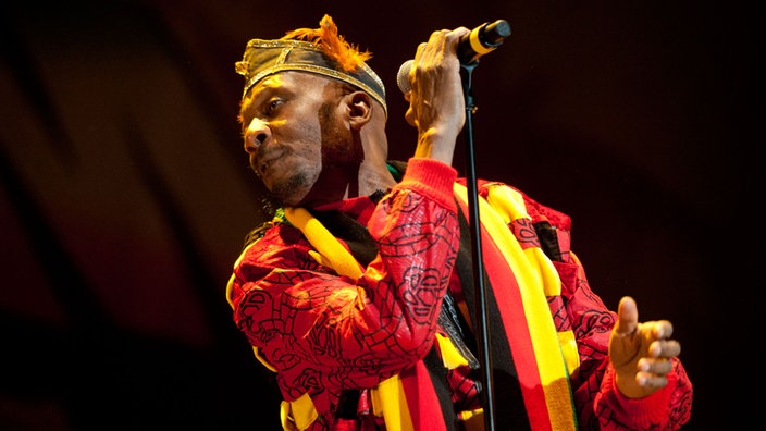 Jimmy Cliff sieht nach links während er den Mikrofonständer hält
