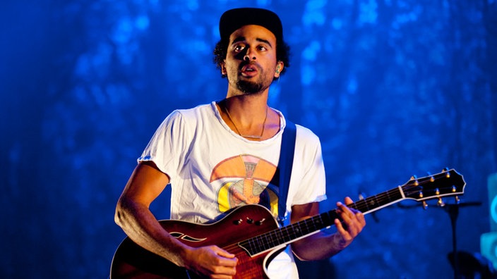 Patrice spielt Gitarre. Er sieht sehr bekifft aus