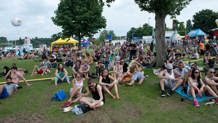 Publikum sitzt auf der Wiese.