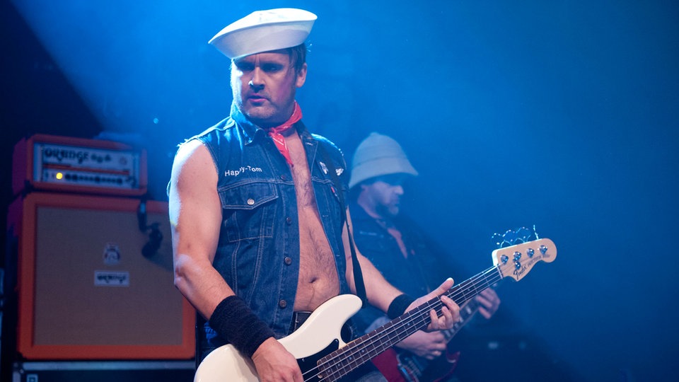 Der Bassist sieht zur Seite während er auf seinem instrument spielt.