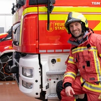 Daniel Aßmann in der Mitte zwischen zwei Feuerwehrpersonen.