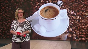 Yvonne Willicks steht im Servicezeit-Studio. Im Hintergrund sieht man eine Grafik, in der eine Kaffeetasse umrandet von Bohnen dargestellt wird.