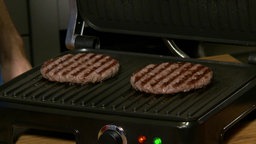 Auf dem Bild ist ein Kontaktgrill mit zwei Burgerpatties zu erkennen.
