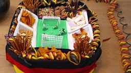 Snacks angerichtet in Form eines Stadions, mit Chips und Knabberzeug auf der Tribüne.