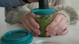 Ein Glas frisches Pesto wird mit einer Vakuumpumpe behandelt.