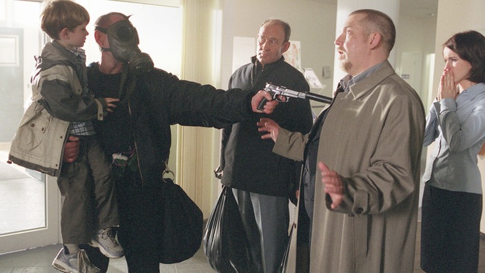 Ein Entführer bedroht Hauptkommissar Freddy Schenk mit einer Pistole