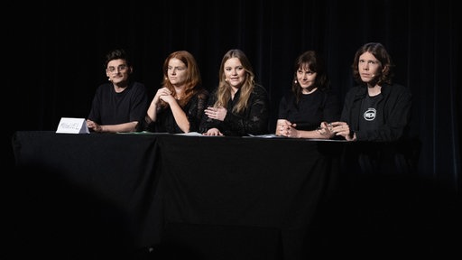 Das Ensemble von "eine show halt" sitzen auf Podium