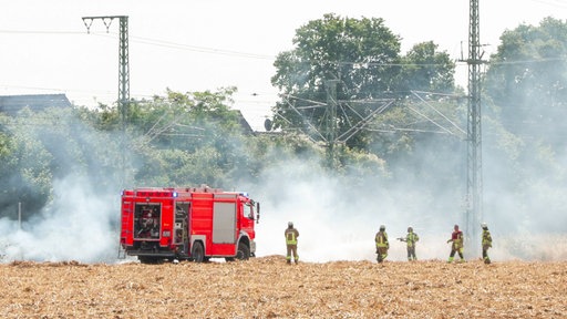 Einsatzkräfte der Feuerwehr löschen einen Brand auf der Bahnstrecke zwischen Düsseldorf und Köln