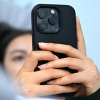 Eine junge Frau liegt mit ihrem Handy auf der Couch und blickt auf das Display