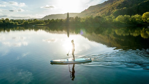 Eine Frau auf einem Stand-Up Paddle auf dem See.