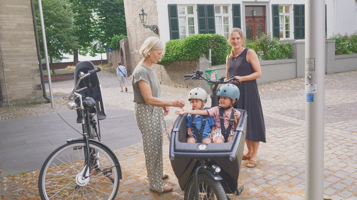 Zwei Kinder mit ihrer Mutter und Großmutter auf dem Kirchenvorplatz.