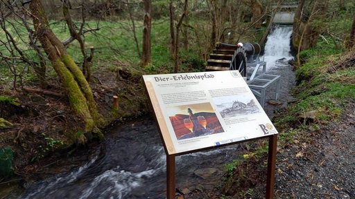 Eine Erklärtafel auf dem Biererlebnispfad in Hallenberg neben dem Flüsschen Nuhne