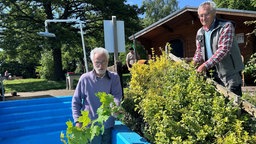 Ehrenamtler schneiden Hecke an Freibad Dusche