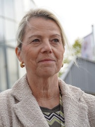 Eine blonde Frau vor einem gläsernen Gebäude.