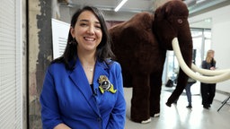 Eine Frau steht vor einem großen, gehäkelten Mammut