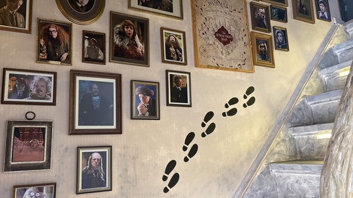 Eine schräge Treppe. An der Wand hängen mehrere Bilder von Charakteren aus den Harry-Potter-Filmen