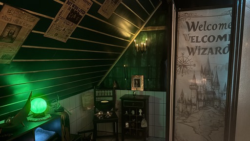 Ein dunkles Badezimmer mit grüner Lampe und einer Dusche auf der "Welcome Wizards" steht