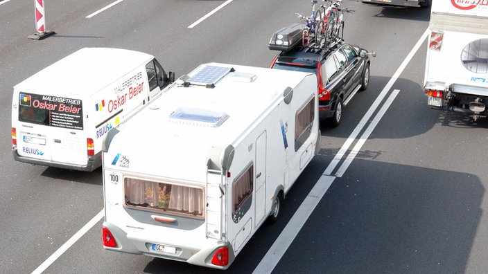 Das Bild zeigt ein Auto mit Caravan auf der Autobahn.