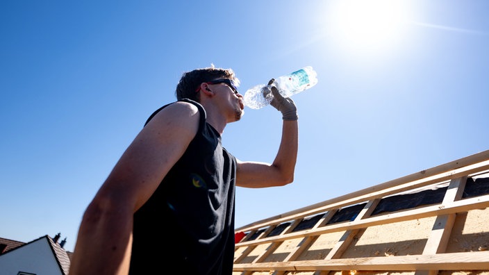 Ein Mann trinkt Wasser unter der sengenden Sonne