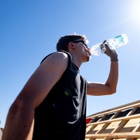 Ein Mann trinkt Wasser unter der sengenden Sonne