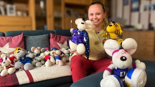 Eine Frau, WDR-Tonassistentin Katharina Ruß, sitzt auf einem Sofa umringt von verschiedenen Diddl-Stoffmäusen