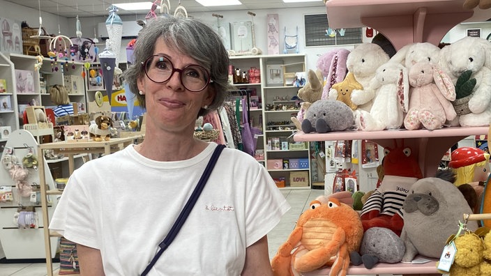 Eine Frau, Steffi Stöhr, Inhaberin von Pur Natur in Moers, steht in einem Spielwarengeschäft neben einem Aufsteller mit Kuscheltieren