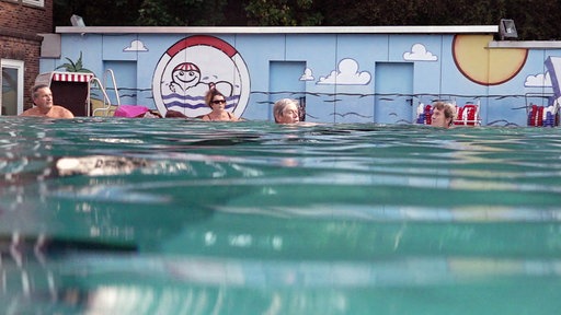 Ein Freibad, in dem einige Menschen schwimmen. 