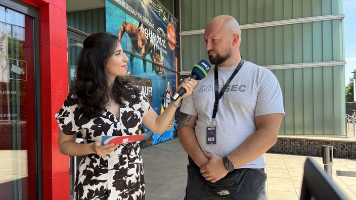 WDR-Reporterin Nastaran Amirhaji interviewt Security-Mitarbeiter Andreas Bolender vor dem Eingang des Aquaparks in Oberhausen 