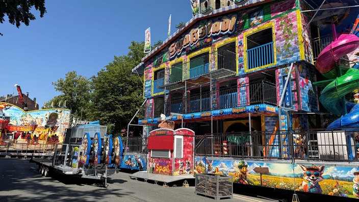 Ein buntes Fahrgeschäft, das von außen wie ein Haus aussieht, darüber steht "Spaßstadl".