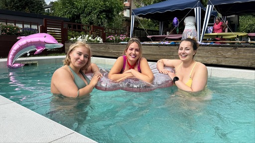 Veranstalterin Janina Gierke und zwei Partygästinnen im Pool. Alle lächeln in die Kamera.