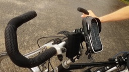 Das Bild zeigt einen Fahrradlenker, an dem eine Handyhalterung angebracht wurde. 