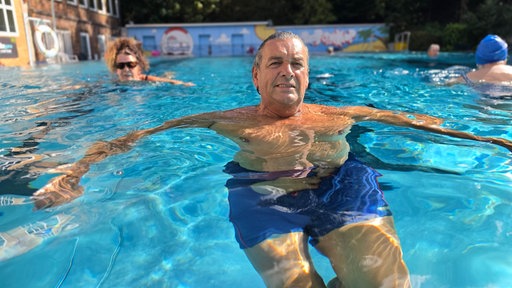 Portait von Ralf Kneip, ein Mann blickt aus einem Schwimmbecken in die Kamera