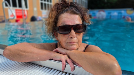 Portait von Alfreda Kneib, eine Frau in Badekleidung blickt vom Beckenrand aus in die Kamera 