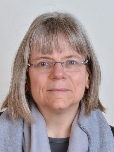Susanne Hüttemeister, kurze grau-blonde Haare mit Pony, eckige, rahmenlose Brille und grauem Schal um den Hals, blickt nach vorne
