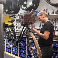 Eine Zweiradmechanikerin schraubt an einem Rad.