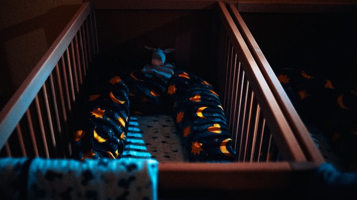 Ein Kitabett mit Kissen in einem abgedunkelten Raum.