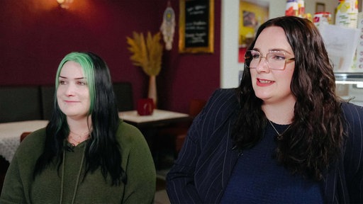 Zwei junge Frauen, Danah und Lara Jäger, sitzen in einem Café