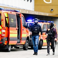 Einsatzwagen und drei bewaffnete, uniformierte Polizisten stehen vor dem Wilhelm-Dörpfeld-Gymnasium.