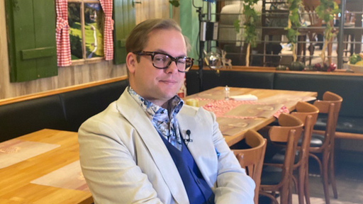 Der ehemalige Neonazi Axel Reitz sitzt auf einem Stuhl in einer Gastronomie