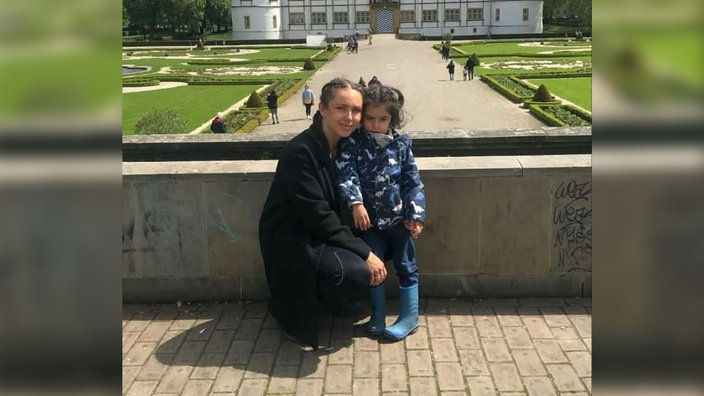 Derya Seyhun kniet neben ihrem Sohn Kian, die beiden machen vor einem Schloss ein Foto und lächeln in die Kamera.