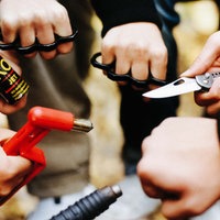 Kinder halten Schlagringe, Messer und Pfefferspray in den Händen.
