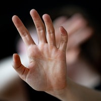 Eine Frau hält schützend ihre Hände vor das Gesicht