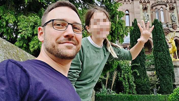 Steven H., ein bärtiger Mann mittleren Alters mit kurzen braunen Haaren, schaut in die Kamera. Neben ihm seine Tochter mit schulterlangen, offenen braunen Haaren. Ihr Gesicht ist verpixelt.